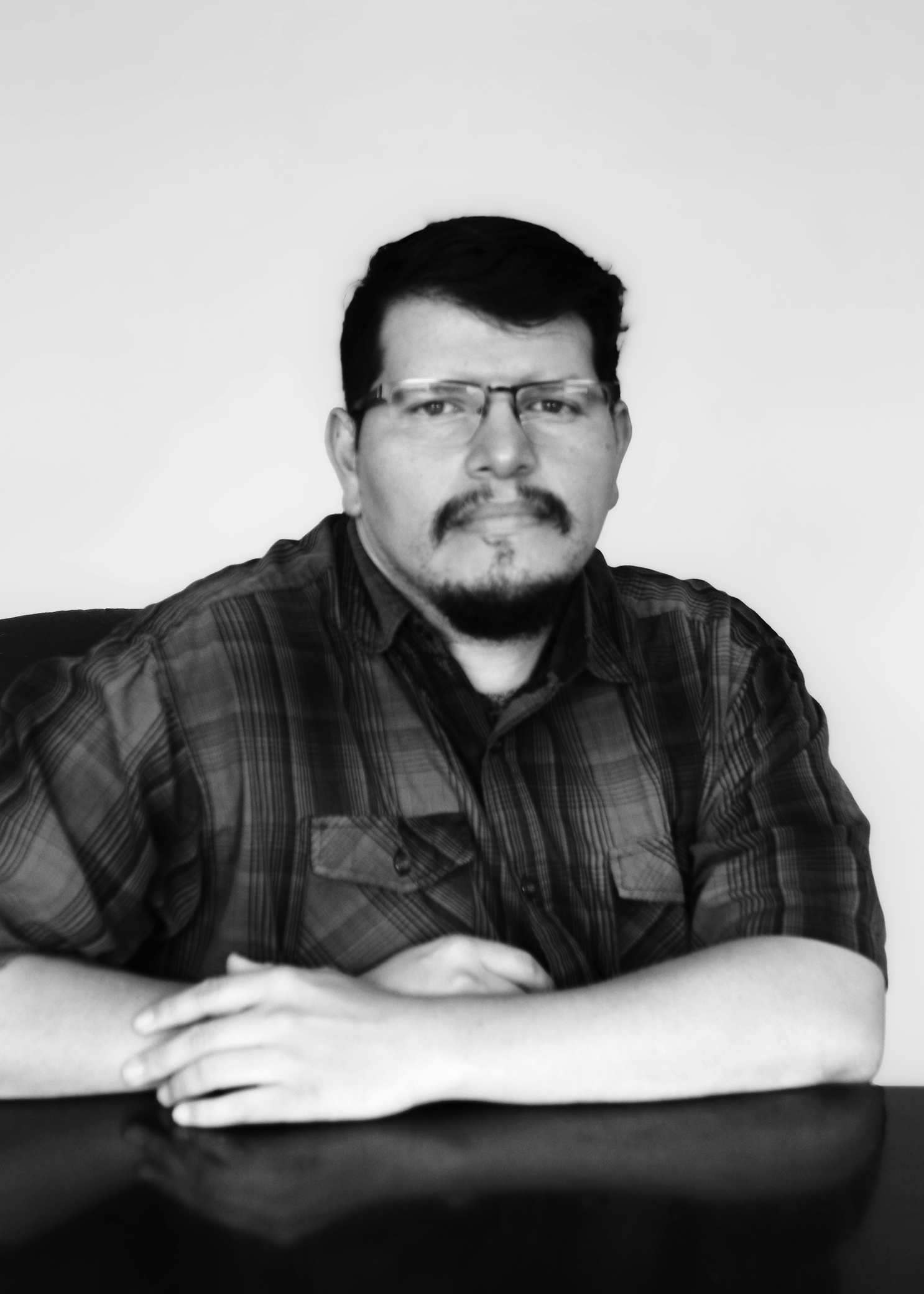 Black and white portrait of a man leaned against a table.